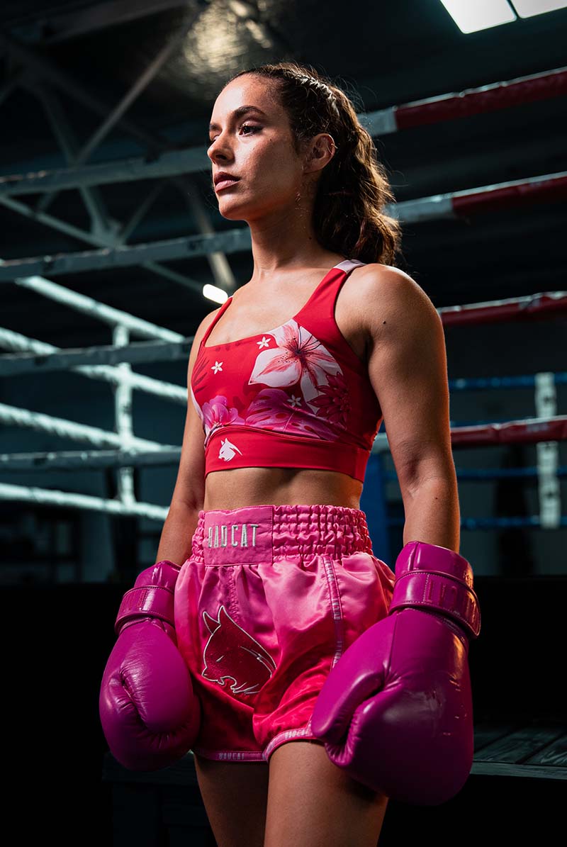 Woman in pink boxing gear standing in a boxing ring.