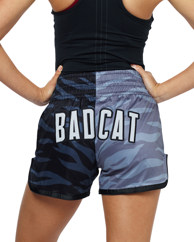 Woman wearing BAD CAT branded fight shorts and boxing gloves on a white background