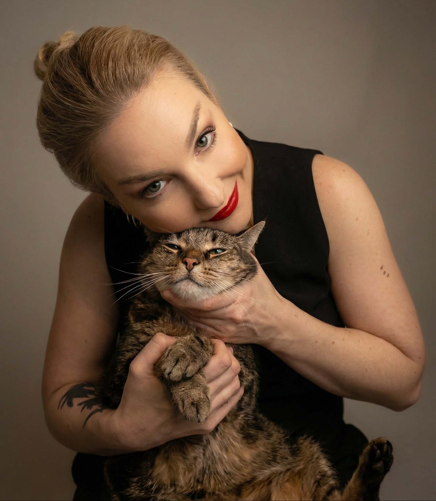 Woman holding a cat against a neutral background