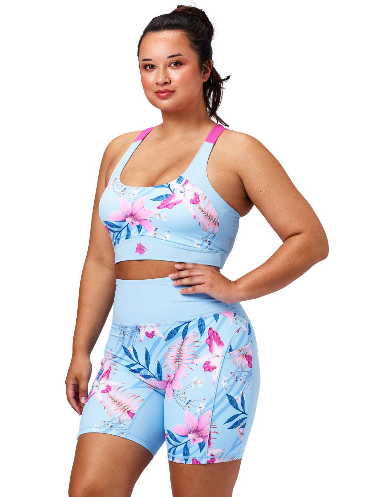 Woman wearing a blue floral sports bra and shorts set on a white background