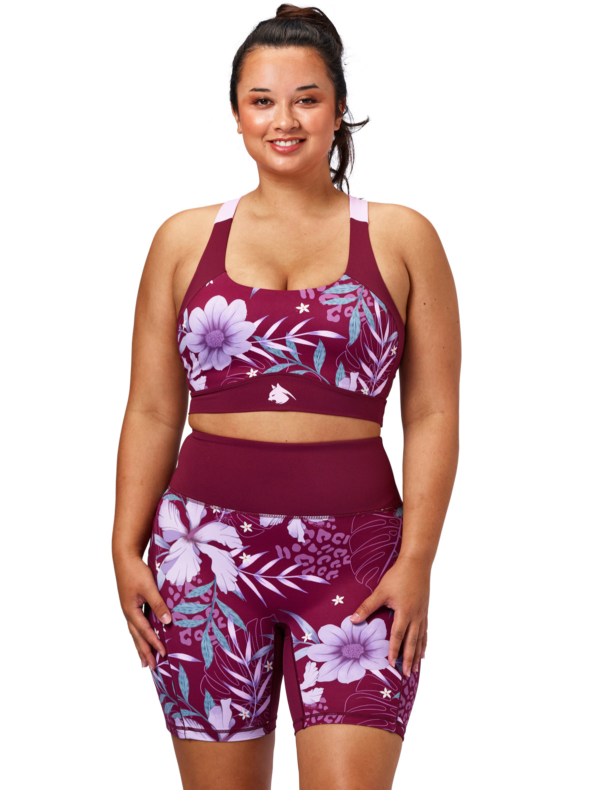Woman wearing a maroon sports bra and shorts with floral design on a white background