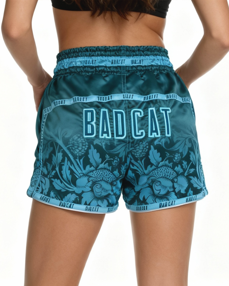 Teal shorts with floral pattern and 'BAD CAT' text on a white background