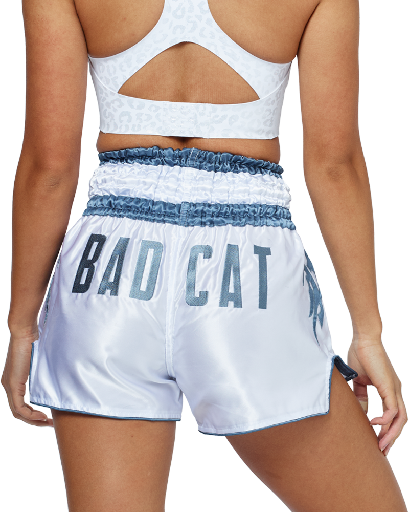 Woman wearing white BAD CAT Muay Thai shorts and boxing gloves on a white background