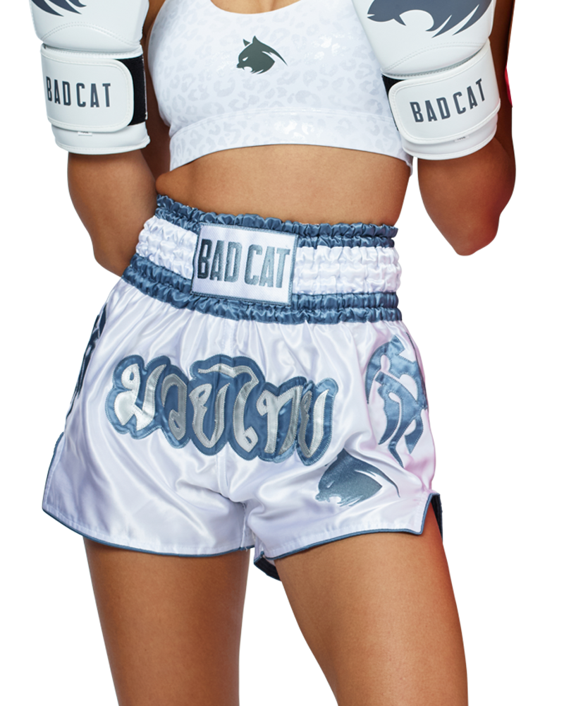 Woman wearing white BAD CAT Muay Thai shorts and boxing gloves on a white background