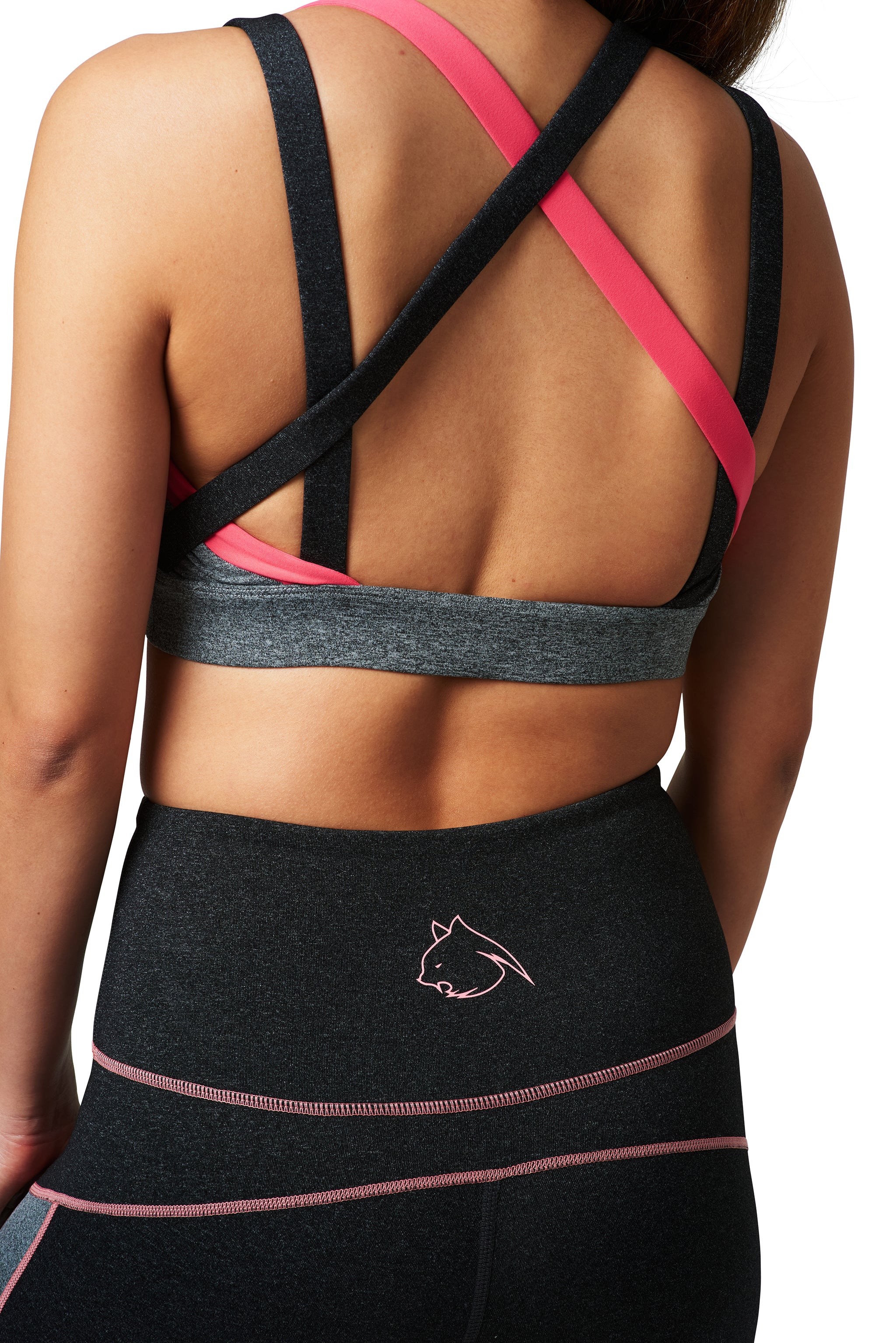 A woman wearing a gray sports bra with coral accents, paired with matching activewear leggings with a visible BAD CAT logo in the back.