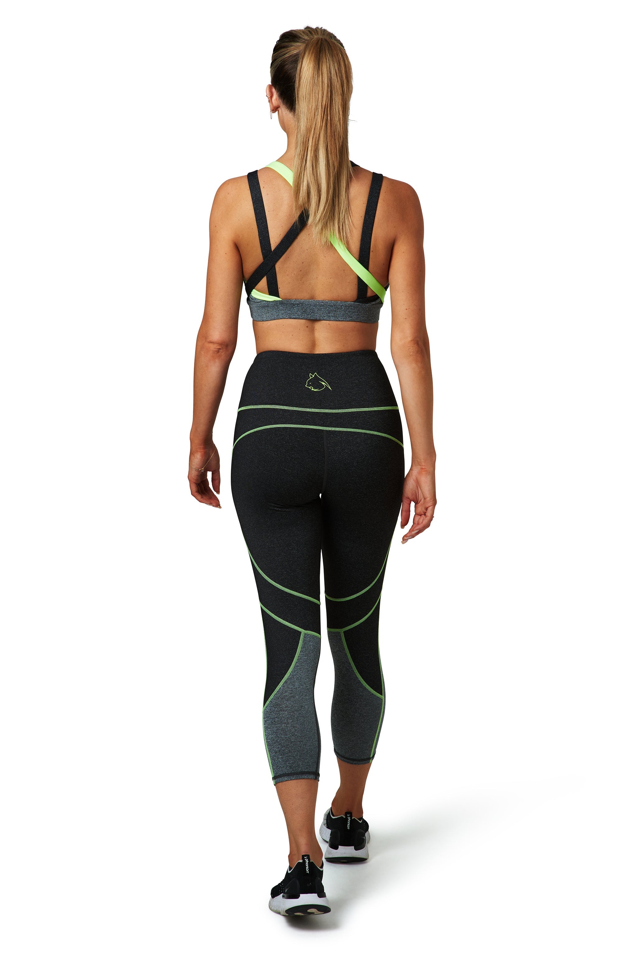 A woman wearing a BAD CAT grey and lime coloured activewear set pictured from behind